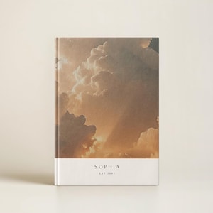 May include: A white journal with a brown and orange cloudy sky image on the cover. The text "SOPHIA EST 2005" is printed on the bottom of the cover.
