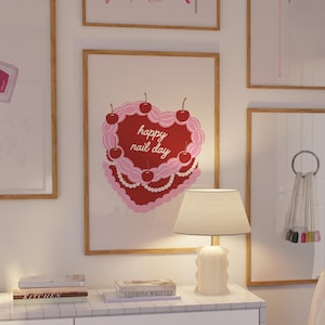 以下が含まれることがあります： ネイルサロンをテーマにした額装されたプリントのコレクション。プリントには、マニキュア、ネイルツール、そして「ハッピーネイルデー」という文字が書かれたハート型のケーキの画像が描かれています。