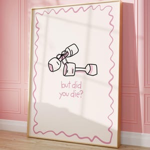 Puede incluir: Un estampado enmarcado con una ilustración de dibujos animados de pesas y el texto "but did you die?" La obra de arte es en blanco y rosa, sobre un fondo rosa claro con un borde rosa ondulado. El marco es dorado.