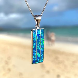 Puede incluir: Un collar de cadena de plata con un colgante rectangular con una piedra de ópalo azul y verde.