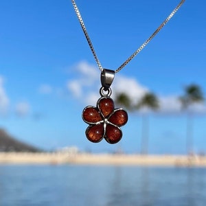 May include: A silver chain necklace with a brown flower pendant. The flower has five petals and is made of wood.