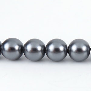 May include: A strand of gray pearl beads. The pearls are round and smooth, and they are strung on a clear thread.