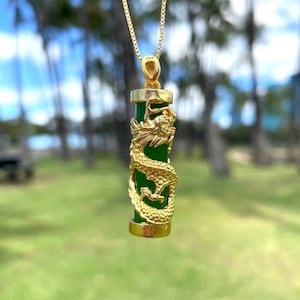 Op de afbeelding: Een gouden ketting met een groene jade hanger met een gedetailleerd gouden drakenontwerp.