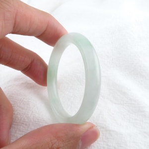Könnte beinhalten: Ein hellgrünes Jade-Armband. Das Armband ist glatt und poliert.