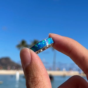 May include: A silver ring with a blue and green opal inlay.