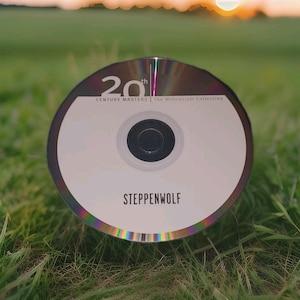 Peut inclure: Un disque compact avec le texte "20th Century Masters The Millennium Collection" et le nom du groupe "Steppenwolf". Le disque est posé sur de l'herbe verte, avec un coucher de soleil flou en arrière-plan.