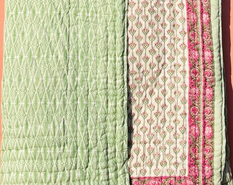 May include: A green and white cotton quilt with a diamond pattern on one side and a floral pattern on the other. The floral side has a pink border.