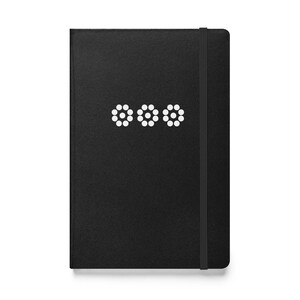 May include: Black leather-bound journal with a white dotted design on the front cover. The journal has a black elastic closure.