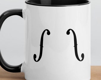 May include: White ceramic coffee mug with a black rim and handle. The mug has a black graphic of two treble clefs on the front.