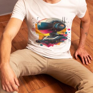 May include: A white t-shirt with a colorful graphic of a robot with a large head and a retro-style design. The robot is wearing a helmet and has a cassette player on its chest.