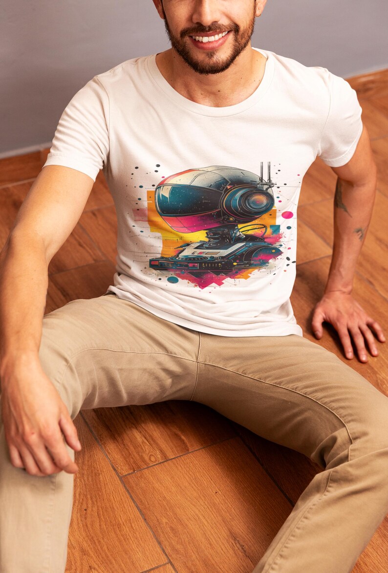 May include: A white t-shirt with a colorful graphic of a robot with a large head and a retro-style design. The robot is wearing a helmet and has a cassette player on its chest.
