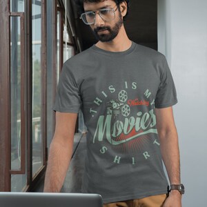 May include: A dark grey t-shirt with a vintage-style graphic of a movie projector and the text "This is my watching movies shirt".