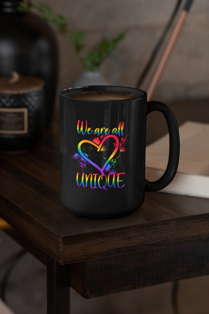 May include: Black coffee mug with a rainbow heart and the text "We are all unique".