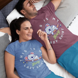 以下が含まれることがあります： 「This is my being lazy shirt」というテキストとコアラのグラフィックがプリントされた、ブルーとマルーンのペアのTシャツを着たカップルです。