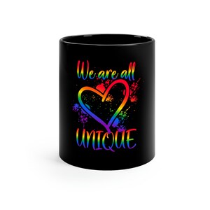May include: Black coffee mug with a rainbow heart and the text "We are all UNIQUE".