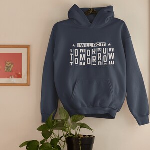 K&ouml;nnte beinhalten: Ein marineblauer Hoodie mit einer wei&szlig;en Grafik, auf der "Ich werde es morgen tun" steht, wobei das Wort "morgen" durcheinander geschrieben ist.