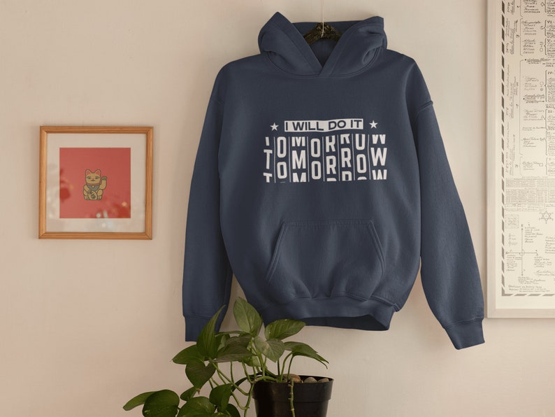 K&ouml;nnte beinhalten: Ein marineblauer Hoodie mit einer wei&szlig;en Grafik, auf der "Ich werde es morgen tun" steht, wobei das Wort "morgen" durcheinander geschrieben ist.