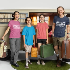 May include: A family of four standing in front of a vintage van, each wearing a t-shirt with a humorous saying. The shirts say "I used to have money, now I have kids". The family is holding luggage and a picnic basket, suggesting they are going on a trip.