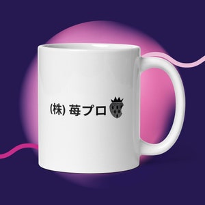 Może przedstawiać: Biały ceramiczny kubek z czarnym uchwytem. Kubek zawiera japoński tekst i czarno-białą ilustrację truskawki z koroną. Kubek jest umieszczony na gradientowym tle fioletu i różu.