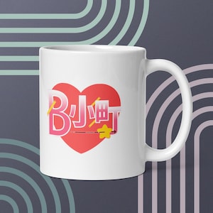 May include: White ceramic mug with a pink heart design featuring the text "BJ 小町" in Japanese characters. The heart has a yellow star and a yellow arrow pointing to the right.