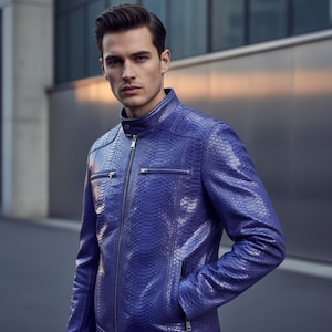 May include: A vibrant blue leather jacket with a snakeskin texture. The jacket features a zip-up front, two chest pockets, and a stand-up collar. The model is wearing the jacket with one hand in the pocket.