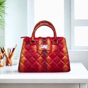 Könnte beinhalten: Eine rote und goldene gesteppte Handtasche mit Schlangenhautmuster. Die Tasche hat einen oberen Henkel und einen Reißverschluss.