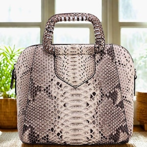 Peut inclure: Un sac à main en peau de serpent avec une poignée au design unique. Le sac est de couleur brun clair avec un motif noir et blanc.