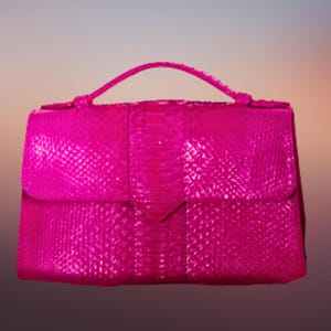 Puede incluir: Un bolso de mano de color rosa brillante con un patrón texturizado que se asemeja a la piel de serpiente. El bolso tiene un solo asa superior y un cierre de solapa.