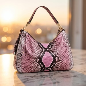 May include: A pink and black snakeskin-patterned handbag with a curved shape and a single handle. The bag has gold-colored hardware and a zipper closure. The background features a blurred cityscape with a warm, golden light.