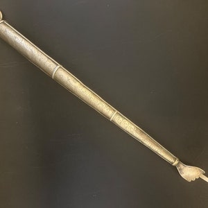 Może przedstawiać: Srebrny, ozdobny, dekoracyjny, ręcznie wykonany przedmiot religijny z pierścieniem na górze.