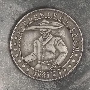 May include: Silver coin with a skull wearing a sombrero and the text "E PLURIBUS UNUM" and "1881".
