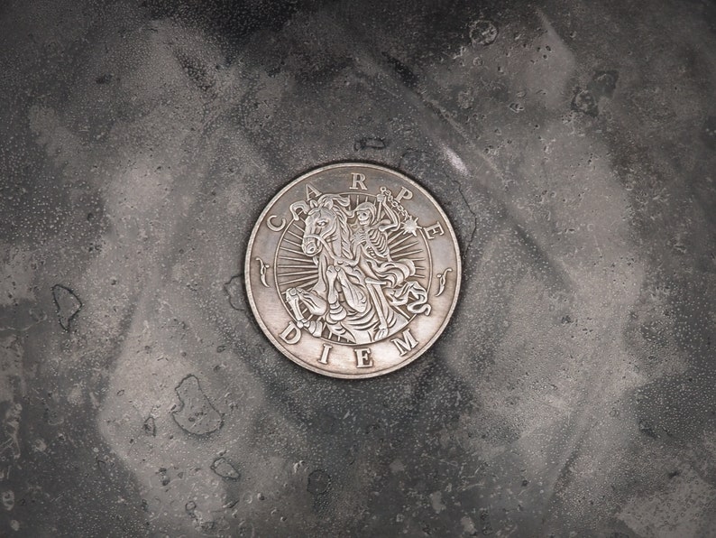 May include: A silver coin with the Latin phrase "Carpe Diem" and a depiction of a skeleton riding a horse.