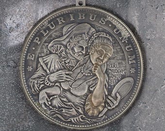 May include: A silver coin with a detailed engraving of two figures, a man and a woman, with the inscription "E PLURIBUS UNUM" around the edge. The inscription "PERI CYLOSYM AMOR EST" is also visible on the coin.