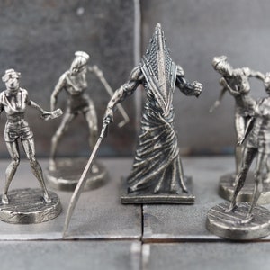 May include: A set of five silver-colored figurines depicting characters from the Silent Hill video game series. The figures include a Pyramid Head figure and four nurse figures.