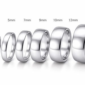 Puede incluir: Se muestran seis anillos plateados de diferentes anchos, que varían de 3 mm a 14 mm. Los anillos están dispuestos en una fila, mostrando sus diferentes tamaños. Los anillos tienen una superficie pulida y reflectante.