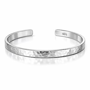 May include: A silver cuff bracelet with a hammered texture. The open-ended bracelet has a rounded shape and is stamped with "925" on the inside. The bracelet is shown on a white background.