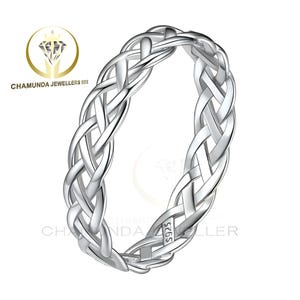Puede incluir: Un anillo plateado con un diseño trenzado. El anillo está hecho de metal brillante y presenta un intrincado patrón tejido. El anillo está marcado con "S925". El anillo es de Chamunda Jewellers.