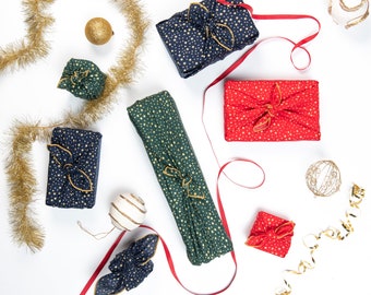 Conjunto festivo de furoshiki com 3 unidades de embalagens pequenas estampadas com estrelas douradas, em tecido reutilizável para embrulhar presentes.