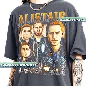 Peut inclure: T-shirt gris foncé avec un graphisme d'un homme aux cheveux roux et le mot "ALISTAIR" en lettres dorées. Le motif comprend plusieurs images du même homme. Le t-shirt porte l'inscription "FAJARTEMPLE".