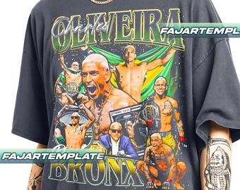 May include: Dark gray t-shirt featuring a collage of images of Charles Oliveira, with the text "OLIVEIRA" in green and "BRONX" in gold. The design includes the Brazilian flag and UFC championship belts.