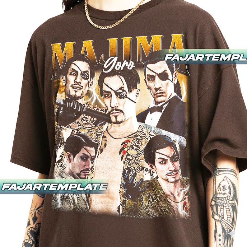 May include: Brown t-shirt featuring a graphic of a character with an eyepatch, with the text "MAJIMA Goro" in gold. The design includes multiple images of the character. The shirt has short sleeves and a relaxed fit.