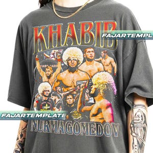 May include: Dark grey t-shirt with a graphic of Khabib Nurmagomedov and the text "KHABIB NURMAGOMEDOV". The design includes images of the fighter and championship belts. The shirt has a vintage, distressed appearance.