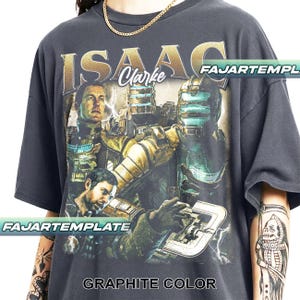 Könnte beinhalten: Graphitfarbenes T-Shirt mit einer Grafik von Isaac Clarke aus dem Videospiel Dead Space. Das Design enthält Bilder von Charakteren und den Text "ISAAC Clarke" in goldfarbenen Buchstaben. Das Shirt hat auch den Text "FAJARTEMPLE" und "GRAPHITE COLOR".