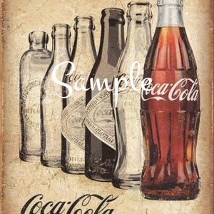 May include: Vintage Coca-Cola advertisement featuring a row of six glass bottles, including a large Coca-Cola bottle with the iconic red and white logo. The bottles are arranged on a textured, aged background with the text "Coca-Cola It's The Real Thing" at the bottom.