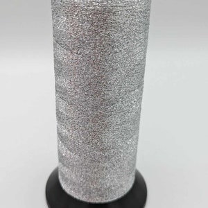 Könnte beinhalten: Eine Spule silbernen Metallic-Garn mit einer schwarzen Kunststoffspule.