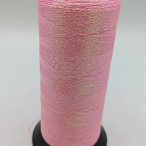 Könnte beinhalten: Eine Spule mit pinkfarbenem, schimmerndem Garn und einer schwarzen Kunststoffspule.