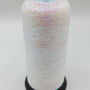 Könnte beinhalten: Eine Spule mit irisierendem weißem Garn mit schwarzem Kunststoff oben und unten. Das Garn hat eine schimmernde, glitzernde Oberfläche.