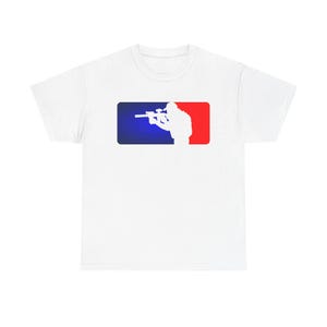 Puede incluir: Una camiseta blanca de manga corta con un gráfico rectangular en el pecho. El gráfico tiene un lado izquierdo azul y un lado derecho rojo, con la silueta blanca de una persona apuntando con un rifle equipado con mira telescópica y silenciador.