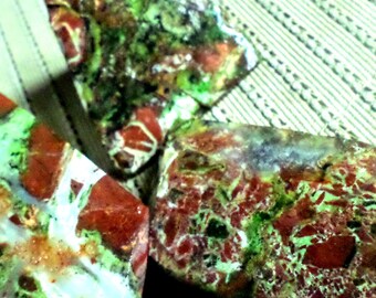 Puede incluir: Tres piedras preciosas pulidas con una mezcla de colores. Las piedras tienen una base blanca y están salpicadas con patrones rojos, verdes y marrones. Las piedras preciosas tienen forma irregular y parecen ser piedras naturales.