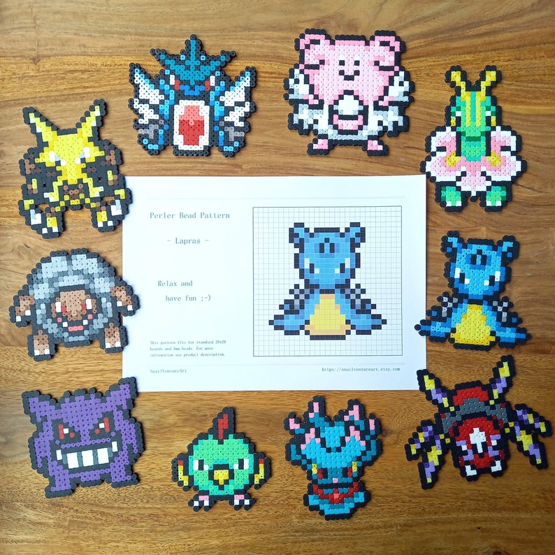 K&ouml;nnte beinhalten: Eine Sammlung von zehn bunten Pixel-Art-Figuren aus verschmolzenen Kunststoffperlen, angeordnet um ein zentrales wei&szlig;es Blatt Papier mit einem Rastermuster f&uuml;r B&uuml;gelperlen einer blauen Kreatur namens Lapras mit Anweisungen.